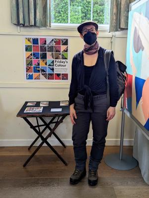 the artist standing next to a poster and display of books and prints